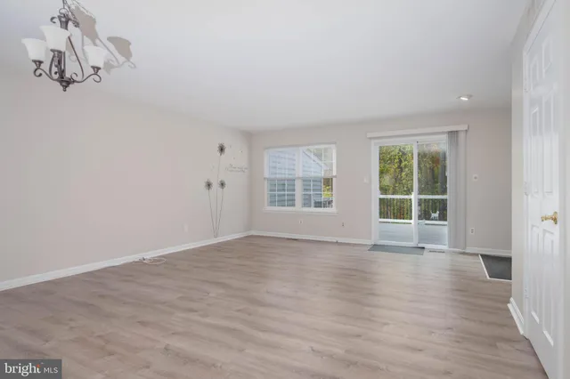 a view of an empty room with wooden floor and windows