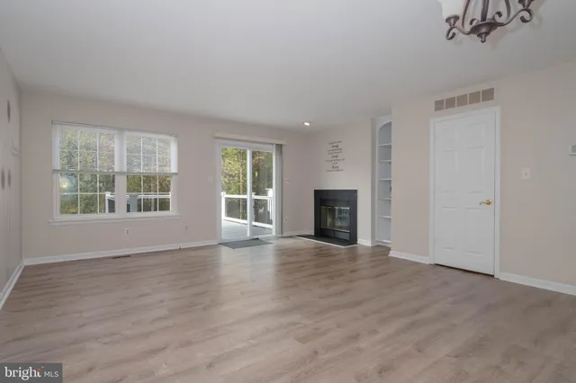 an empty room with wooden floor fireplace and windows