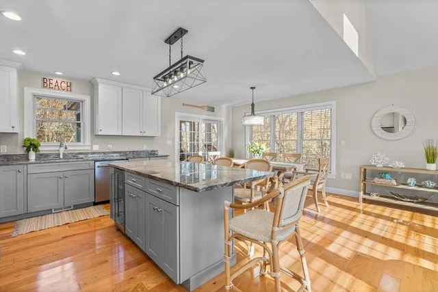 a dining room with wooden floor a chandelier a wooden table and chairs