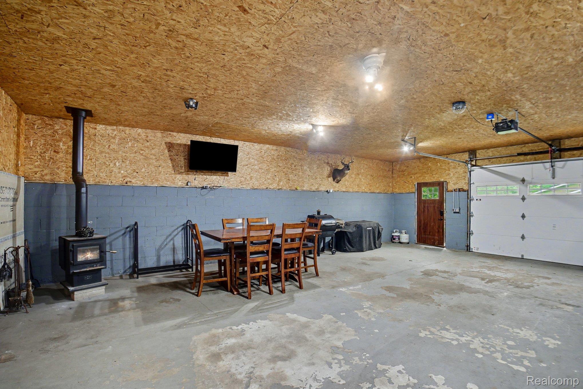 1646 Boy Scout Road Caro, MI 48723 - Photo 17 of 28 Spacious utility room featuring a wood-burning stove, concrete flooring, and a large overhead garage door