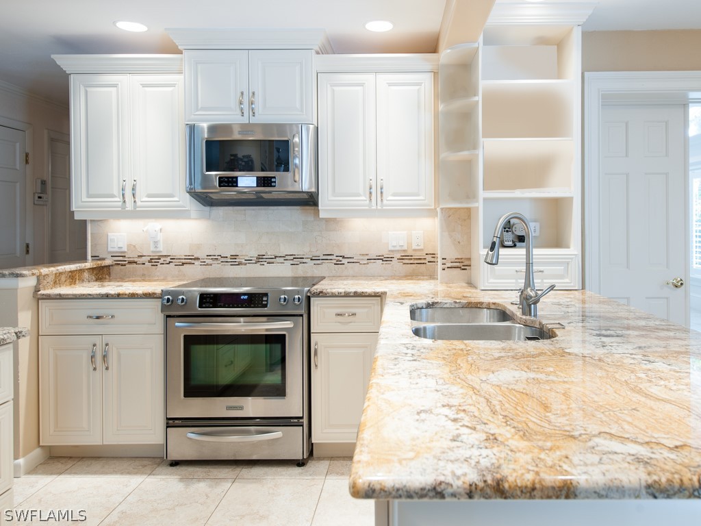 671 Rabbit Road Sanibel, FL 33957 - Photo 14 of 50 a kitchen with granite countertop a stove a sink and a microwave