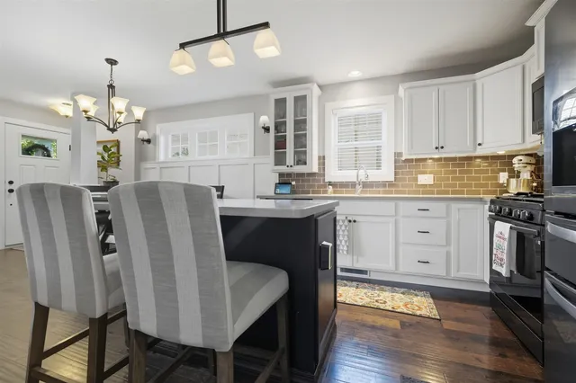 a kitchen with stainless steel appliances granite countertop a dining table chairs refrigerator and cabinets