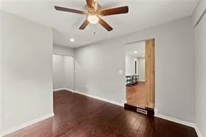 an empty room with wooden floor and ceiling fan