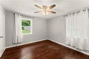 an empty room with wooden floor fan and windows