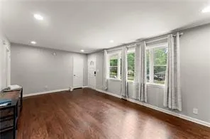 a view of an empty room with wooden floor and a window