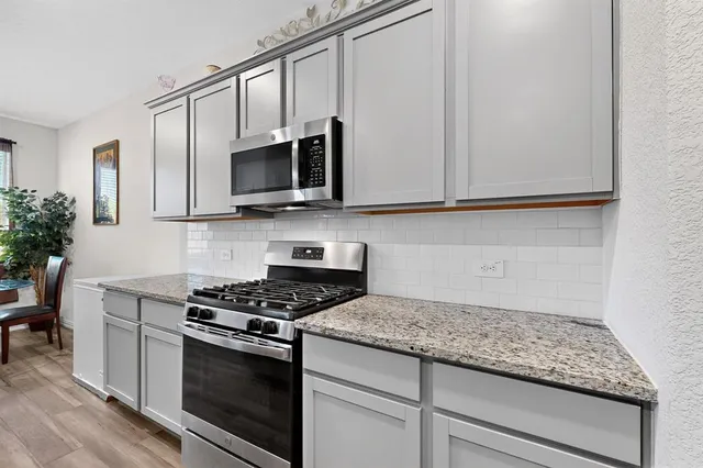 a kitchen with granite countertop cabinets stainless steel appliances and wooden floor