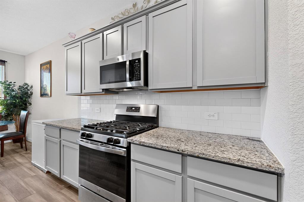 444 Ranchito Pass Fort Worth, TX 76052 - Photo 5 of 18 a kitchen with granite countertop cabinets stainless steel appliances and wooden floor
