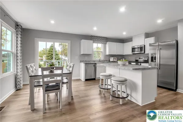 a kitchen with stainless steel appliances granite countertop a refrigerator a stove top oven a sink dishwasher and white cabinets with wooden floor