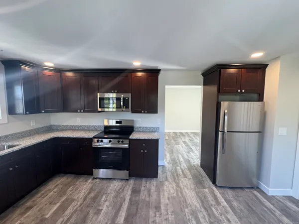 a kitchen with granite countertop a refrigerator and a stove top oven