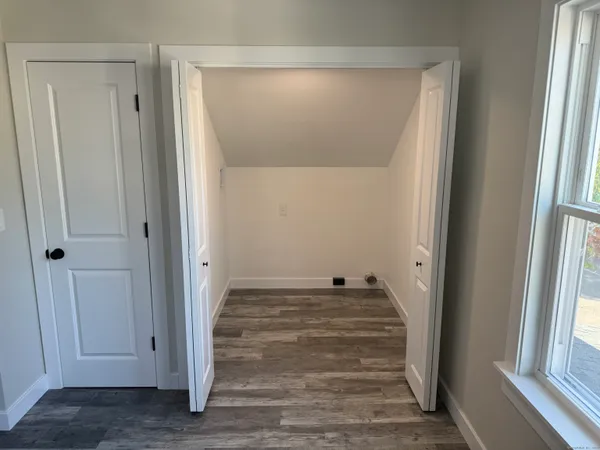 a view of an empty room with wooden floor and a window