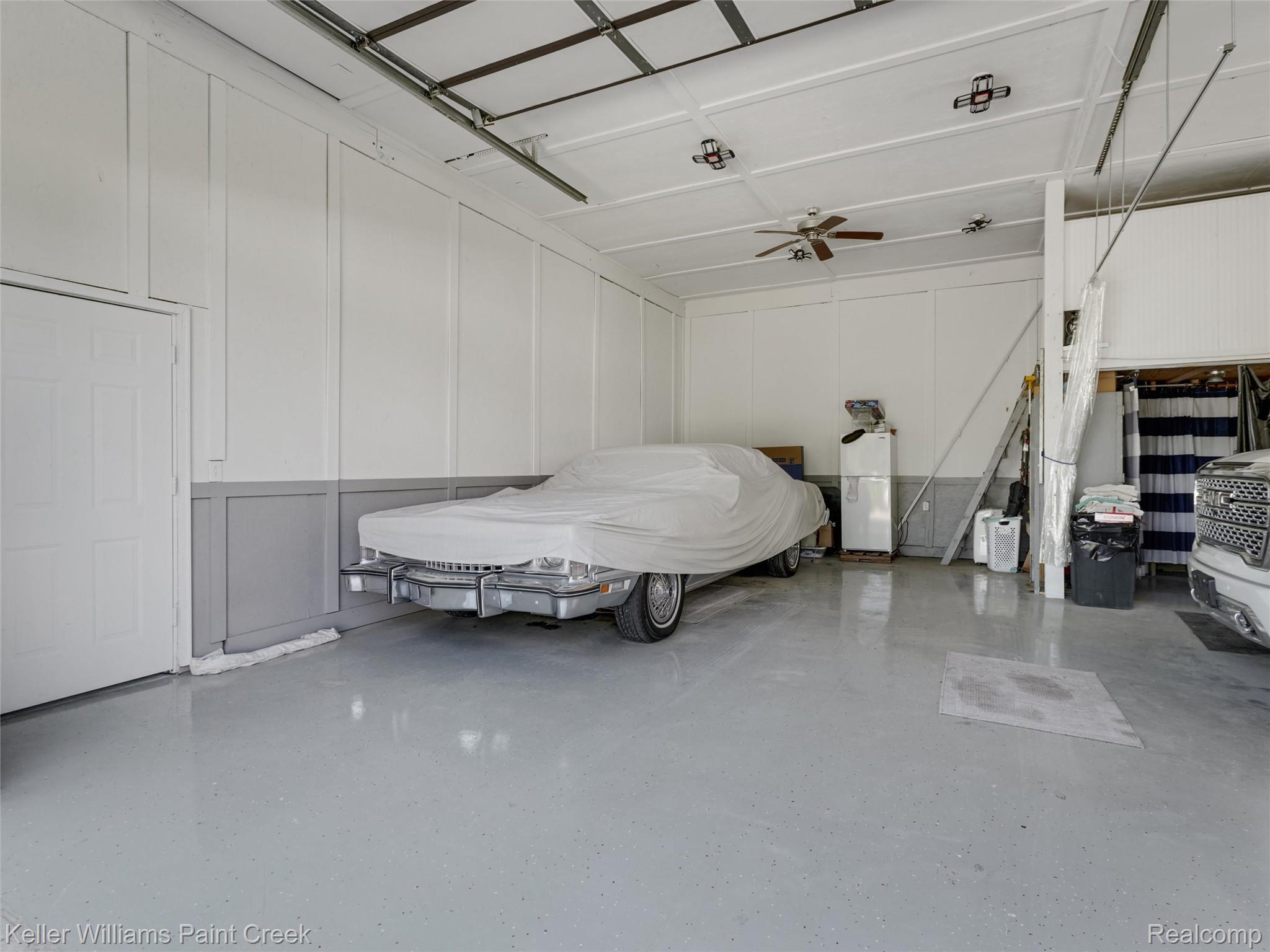 5813 36 Mile Road Romeo, MI 48065 - Photo 44 of 81 Spacious garage featuring a light gray epoxy floor coating, white board-and-batten wall treatment, ceiling fan, and track lighting