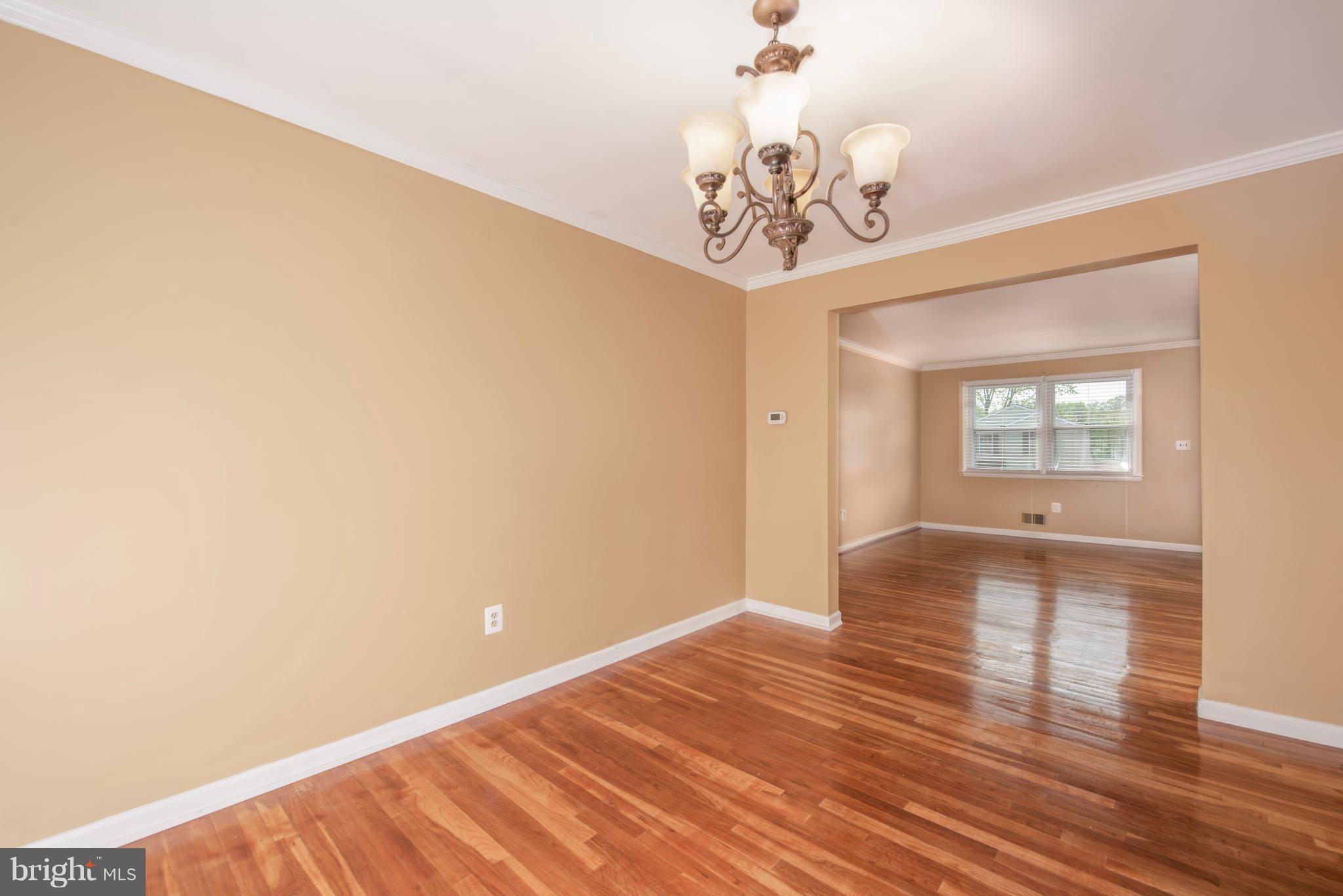 5607 Whitby Road Baltimore, MD 21206 - Photo 7 of 20 a view of an empty room with wooden floor and a chandelier