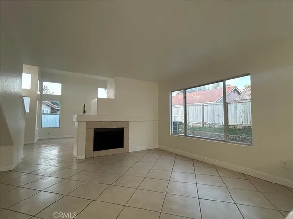 a view of an empty room with a fireplace and a window