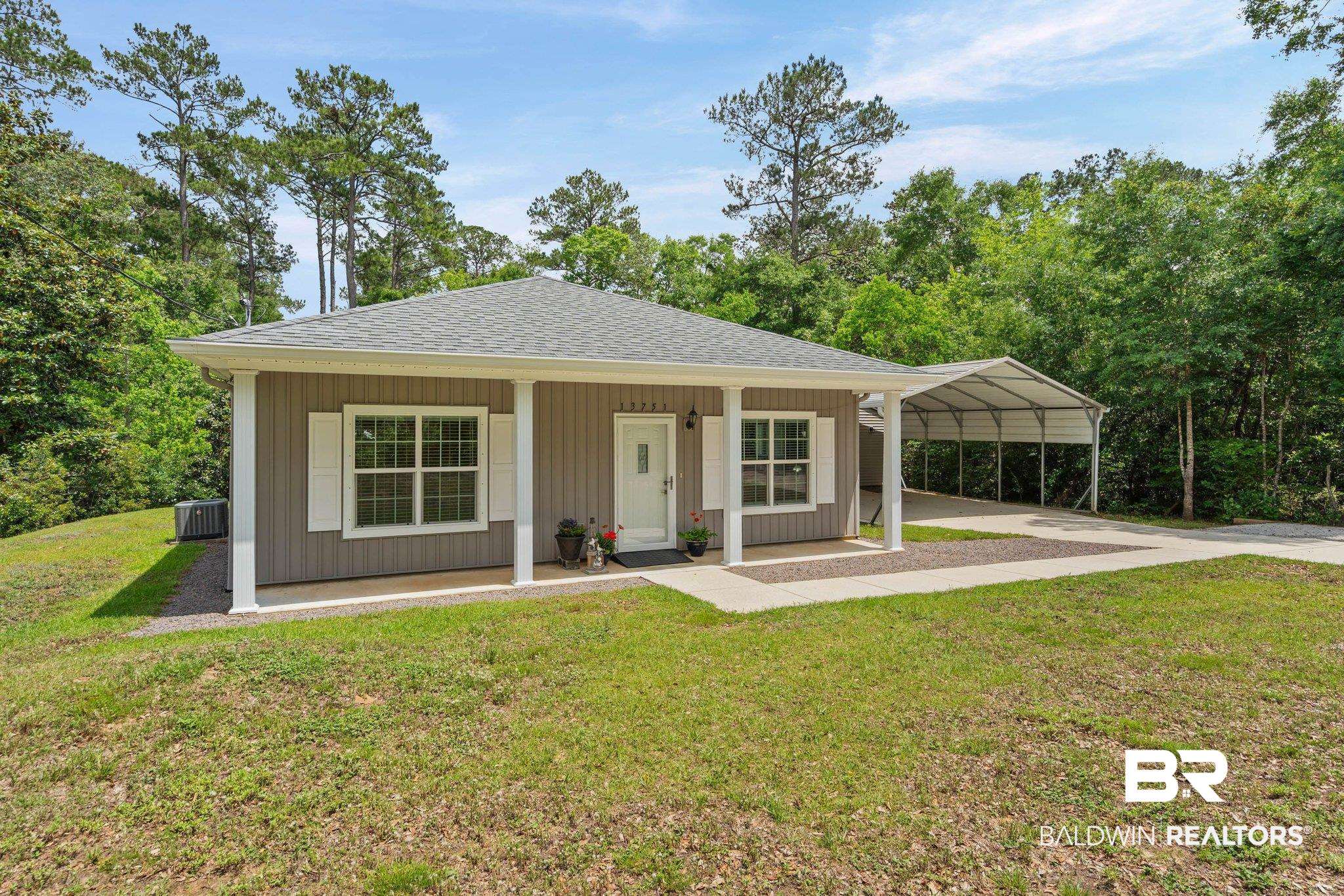 13751 Fish River Acres Circle Foley, AL 36535 - Photo 1 of 26 Contemporary exterior featuring gray siding, white window shutters, and a covered front porch with white columns