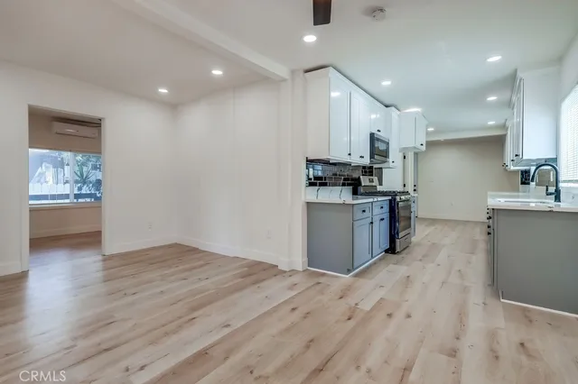 a kitchen with stainless steel appliances granite countertop a stove top oven a sink dishwasher and a refrigerator with wooden floor