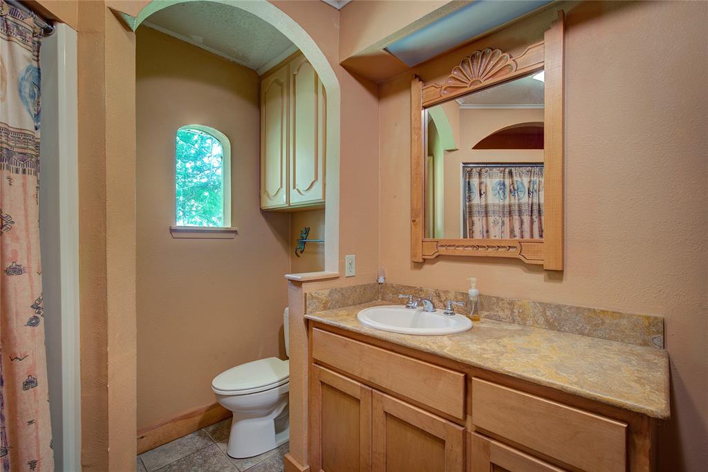 1920 County Rd SE 3370 Winnsboro, TX 75494 - Photo 25 of 40 a bathroom with a granite countertop toilet sink and mirror