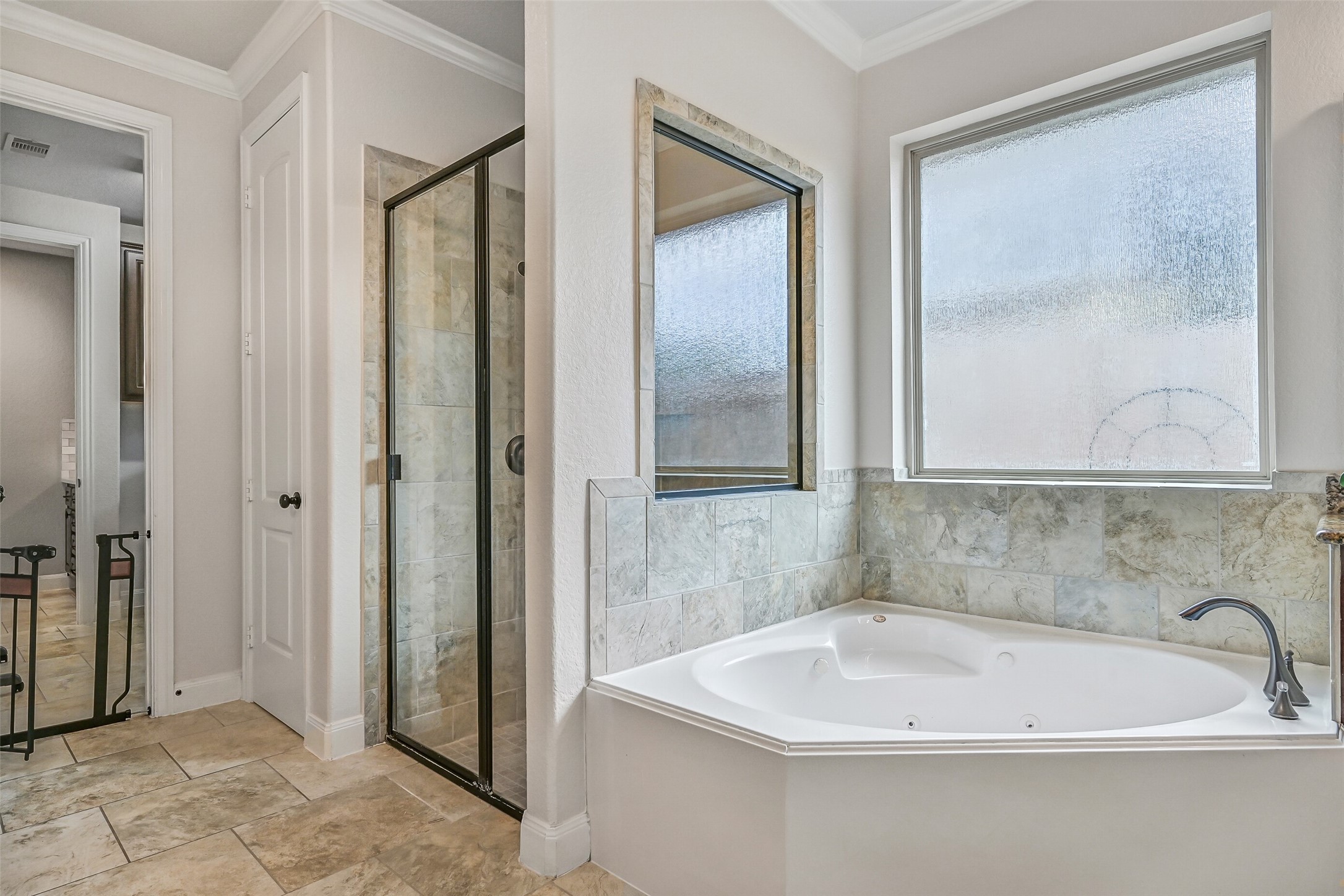 1008 Point Isabel Lane Friendswood, TX 77546 - Photo 32 of 50 A corner jetted soaking tub is framed by frosted windows for soft natural light, complemented by a separate glass enclosed shower with tile surround and built-in shelving.