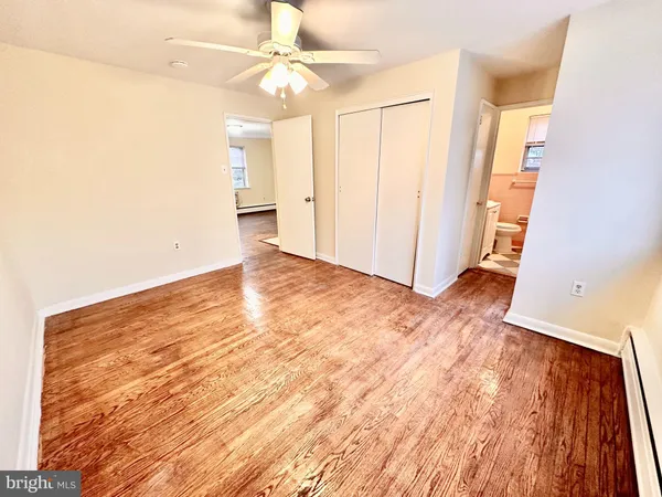 an empty room with wooden floor and ceiling fan