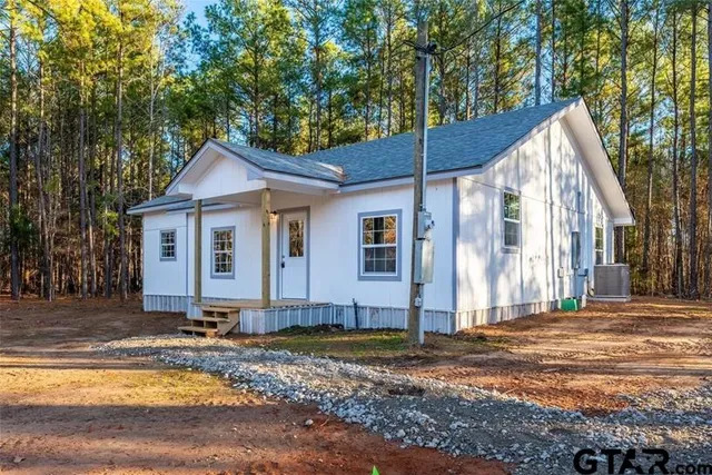a view of a house with backyard and trees
