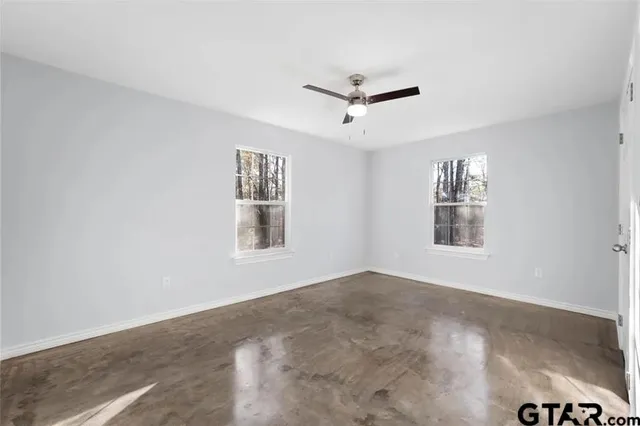a view of a big room with windows and chandelier fan