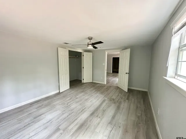 an empty room with wooden floor and windows