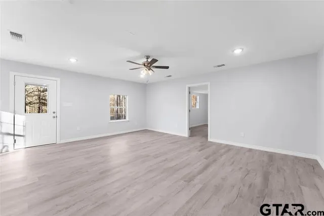 a view of an empty room with a window and wooden floor