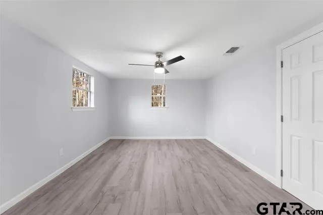 an empty room with a window and a ceiling fan