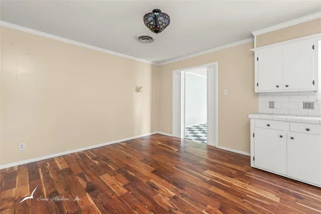 a large kitchen with cabinets and wooden floor