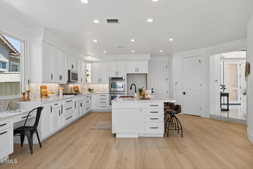 2967 Avenida De Autlan Camarillo, CA 93010 - Photo 18 of 78 a kitchen with stainless steel appliances a stove a sink a refrigerator and white cabinets with wooden floor