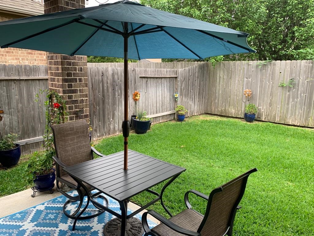 13117 Stoneleigh Terrace Drive Houston, TX 77077 - Photo 14 of 23 a backyard of a house with table and chairs under an umbrella