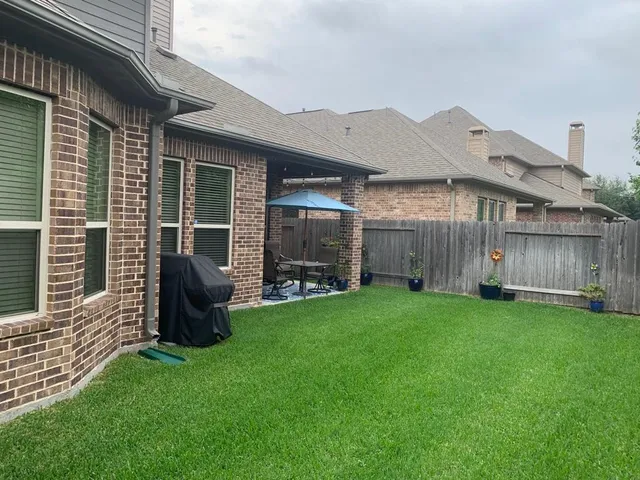 a backyard of a house with table and chairs under an umbrella