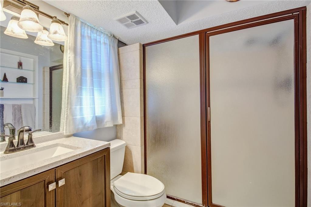 842 Roseate Drive Naples, FL 34104 - Photo 17 of 33 a bathroom with a granite countertop sink toilet and shower