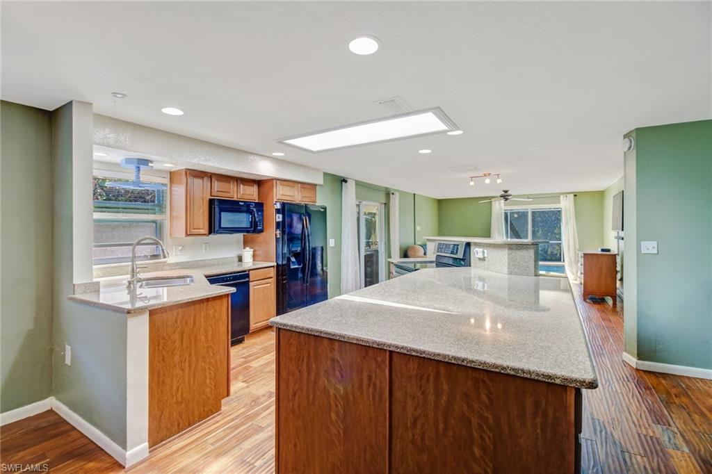 842 Roseate Drive Naples, FL 34104 - Photo 9 of 33 a kitchen with stainless steel appliances kitchen island granite countertop a refrigerator a stove and a sink with wooden floor