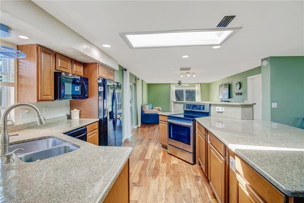 842 Roseate Drive Naples, FL 34104 - Photo 10 of 33 a kitchen with stainless steel appliances granite countertop sink stove refrigerator and cabinets