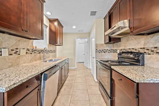 a kitchen with stainless steel appliances granite countertop a stove a sink and a microwave