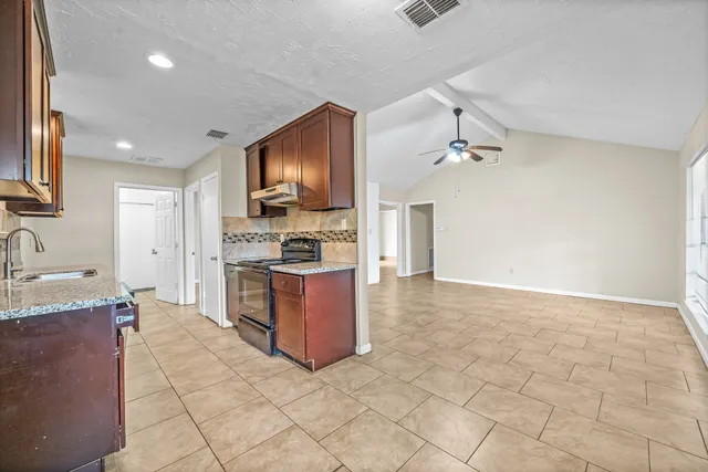 a kitchen with stainless steel appliances granite countertop a stove top oven a sink a counter space and cabinets