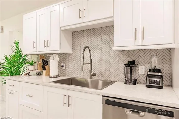 a kitchen with white cabinets a sink and dishwasher