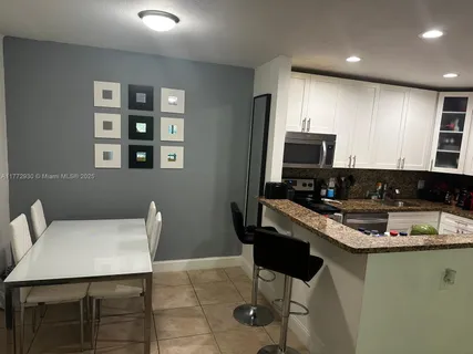 a kitchen with a table chairs refrigerator and microwave