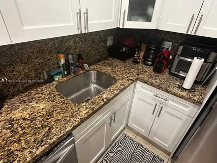 a kitchen with granite countertop a sink and a stove