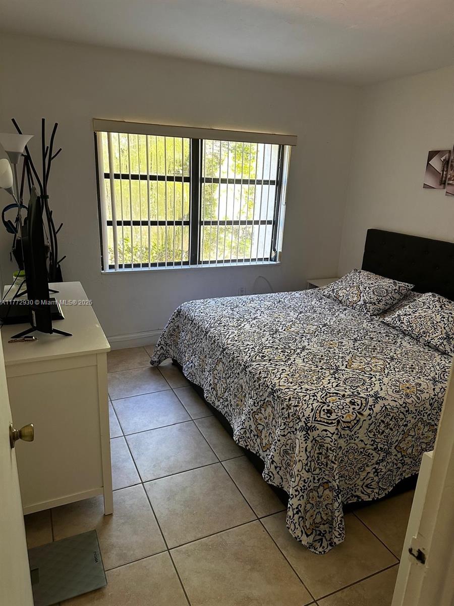 7951 Southwest 104th Street, Unit 210D Miami, FL 33156 - Photo 9 of 15 a bed sitting in a bedroom next to a window