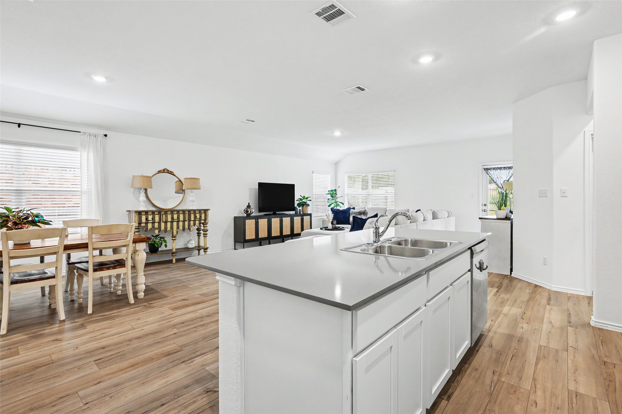 2333 Four Waters Loop Georgetown, TX 78628 - Photo 16 of 35 Open-concept living area featuring wood-finish flooring, recessed lighting, and a kitchen island with a double basin sink and light-toned countertop