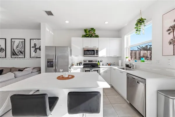 a kitchen with granite countertop a sink stainless steel appliances and white cabinets