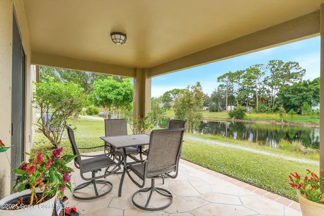 a view of a chairs and table in patio next to a yard