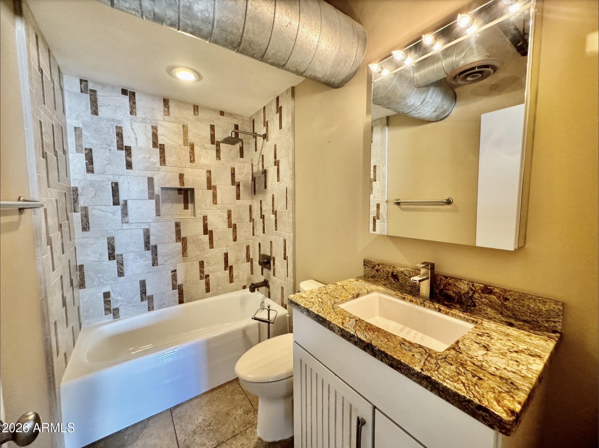 21 East 6th Street, Unit 306 Tempe, AZ 85281 - Photo 5 of 31 a bathroom with a granite countertop sink a toilet a mirror a bathtub and shower