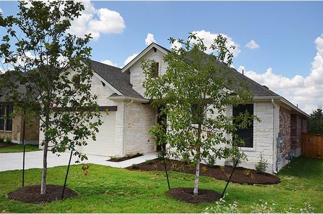 View of front of home featuring a front yard, concrete driveway, brick siding, an attached garage, and a shingled roof