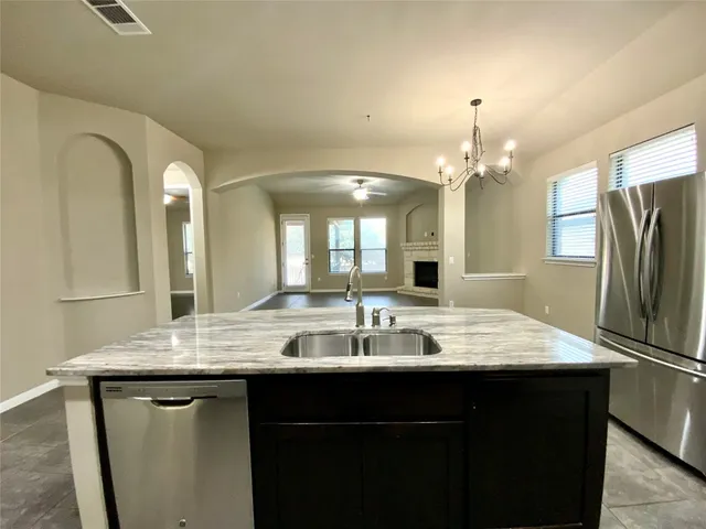 a room with kitchen island granite countertop a sink cabinets and stainless steel appliances