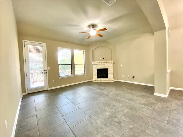 a view of an empty room with chandelier fan and fire place
