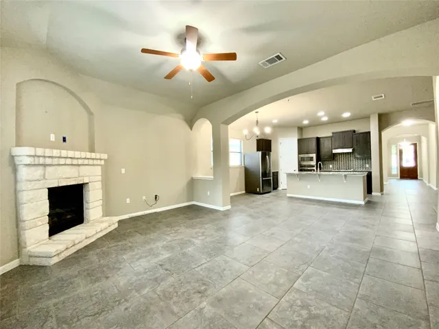 a view of a livingroom with a fireplace a chandelier fan and windows