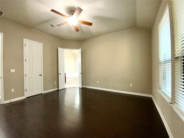 an empty room with wooden floor and windows with curtains