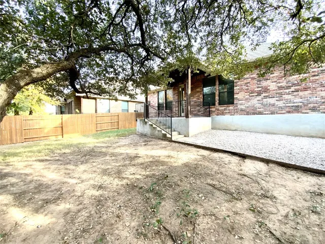 a view of a house with a yard and large tree